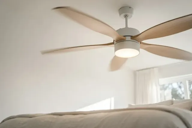 Deckenventilator mit Holzflügeln und integrierter Leuchte an der Decke eines hellen Schlafzimmers