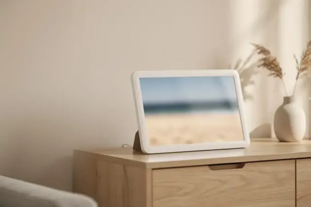 Digitaler Bilderrahmen mit unscharfem Strandfoto auf einem Sideboard aus Eiche